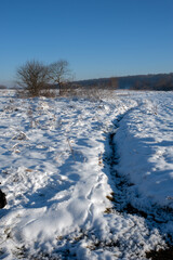 Naklejka premium Panorama of a trail through a snowy winter field. Sunny day after a heavy snowfall.