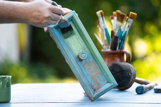 Painting a wooden furniture outdoors, an eco-friendly re-use business.