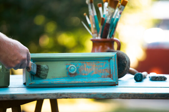 Painting a wooden furniture outdoors, an eco-friendly re-use business.