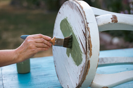 Painting a wooden furniture outdoors, an eco-friendly re-use business.