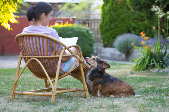 Woman reading a book in her garden with her dog