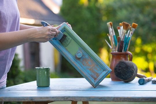 Painting a wooden furniture outdoors, an eco-friendly re-use business.