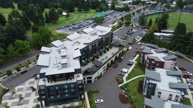 Architectural rooftop structures crown modern multi story mixed use buildings, suburbs Seattle. Paved plazas and parking spaces border the vibrant commercial corridors in Kent, Washington
