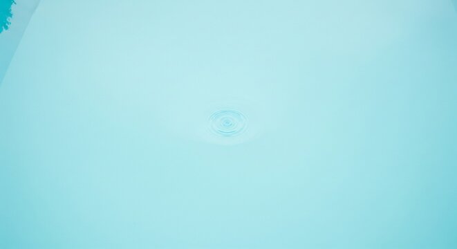 Minimalist view of soft turquoise water with subtle, faint ripples in the center and light shadows.