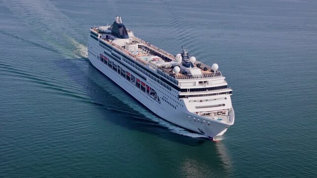 White cruise liner moving through blue water. Drone view for all-inclusive cruise vacation and travel package