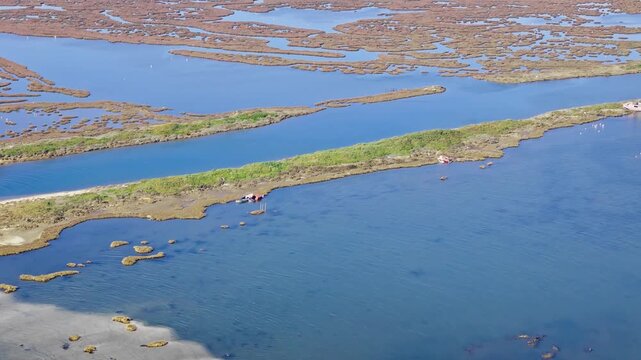 Coastal wetland landscape with lagoon channels, marsh islands and narrow strips of land. Wide aerial view of natural habitat and calm blue water