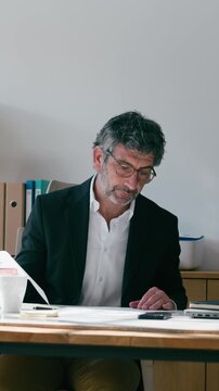 Video of mature elegant businessman working on a computer while taking notes in the office