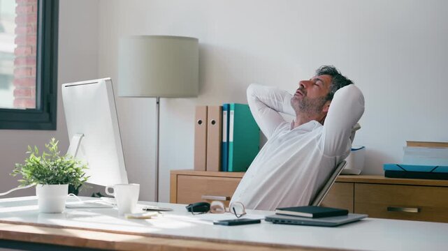 Video of exhausted businessman stretching while working on a computer in the office