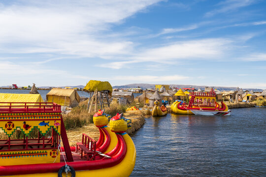 Traditional colorful totora reed boats with puma heads docked at the Uros floating islands village on Lake Titicaca, Puno, Peru