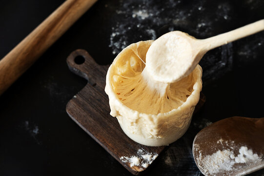 Homemade sourdough starter culture with a wooden spoon.