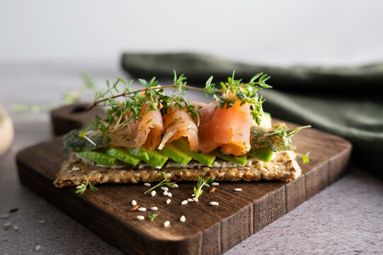Close-up of crunchy crispbread with salmon, avocado, and fresh cress.