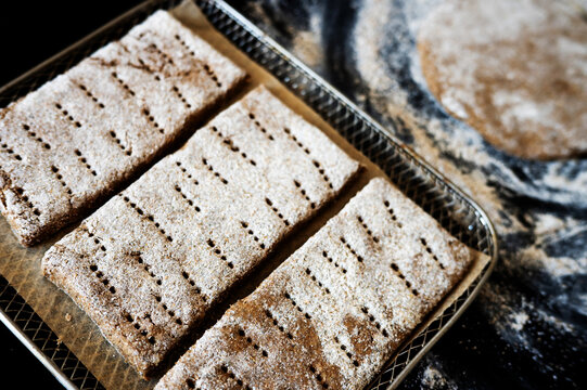 Row of raw rectangular Finnish rye flatbreads on a baking sheet.