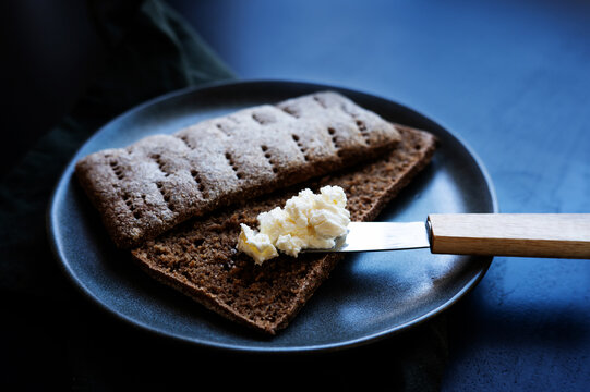 Baked Finnish rye flatbread with cream cheese on a dark background.