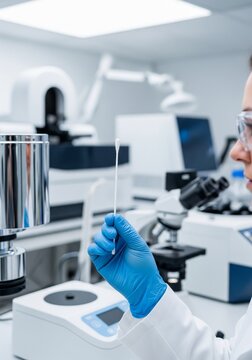 Close-up of laboratory worker holding test swab in modern diagnostic laboratory. Medical technician preparing sample for analysis near microscope and lab equipment.
