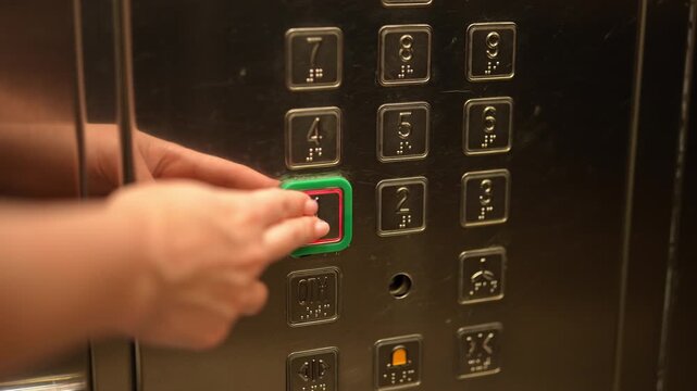 Close-up of woman hand pressing first floor button in elevator. Finger pushing illuminated button on stainless steel control panel. Modern lift interior. Concept of choice and starting point.