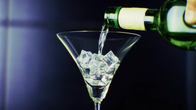 Pouring Alcoholic Drink From Bottle Into Martini Glass With Ice.  Cocktail Preparation. Refreshing Beverage