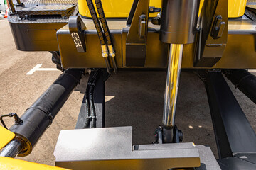 Yellow wheel loader heavy duty dozer blade mechanism. Modern construction machinery steel snow plow push frame section with hydraulic cylinder tilt and industrial vehicle engineering details. © NastyaPhoto
