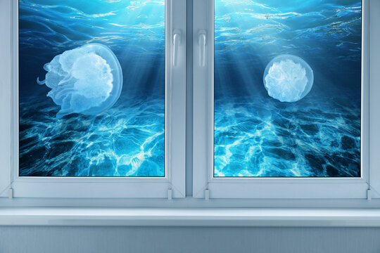 Surreal view from a window showing two jellyfishes swimming underwater in a blue ocean with light rays