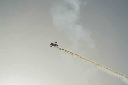 Biplane performing aerobatic maneuver with smoke trail