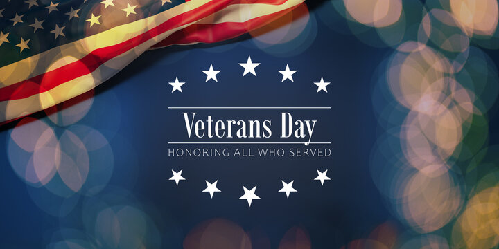 The wrinkled flag of the USA draped onto a flat dark blue surface with a bokeh light overlay and the text  "Veterans Day - Honoring all who served"