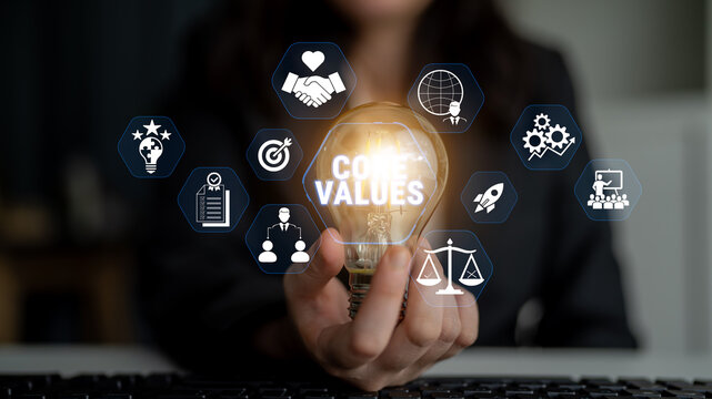 Hand Holding a Light Bulb with Core Values and Business Icons Representing Innovation, Teamwork, Growth, and Ethical Principles in a Modern Workplace Setting Fluxor.