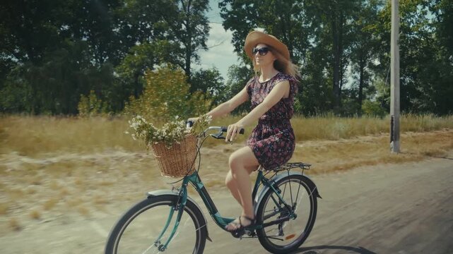Woman Riding Vintage Bicycle With Flowers Basket Country Road. Leisure And Adventure. Nature Exploration Summer Cycling Trip