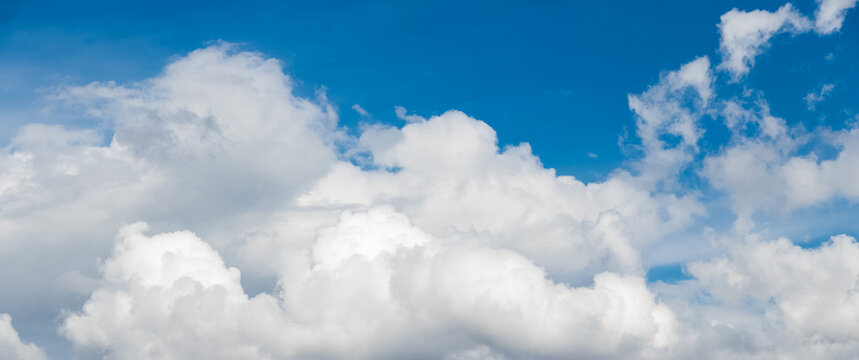 Panoramic vivid blue sky with massive white cumulus clouds at bottom of frame