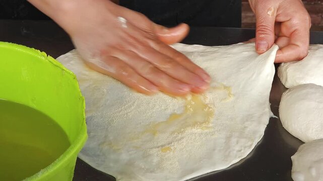 Moroccan Woman Preparing Traditional Msemen Flatbread Dough by Hand. Close-up video of a woman's hands stretching and oiling dough while preparing traditional Moroccan msemen (msemmen) flatbread. 