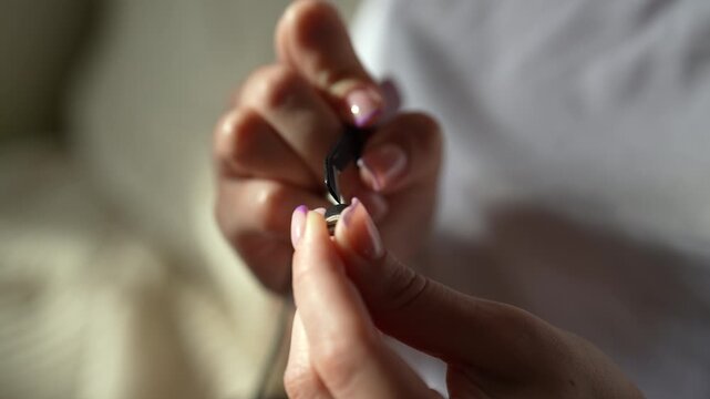Female hands holding broken phone charging cable, inspecting damaged connector with exposed wires before repair. Concept of planned obsolescence and need for gadget maintenance, close-up, slow motion.