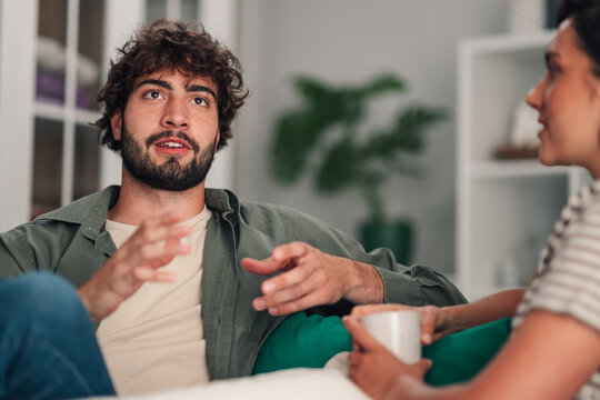 Young man discussing with woman, gesticulating while sharing ideas during a casual conversation indoors