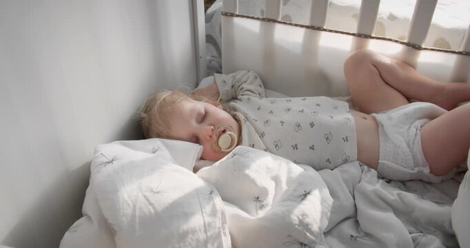 Daytime nap of toddler girl in crib at home. Regular sleep routine for growing child