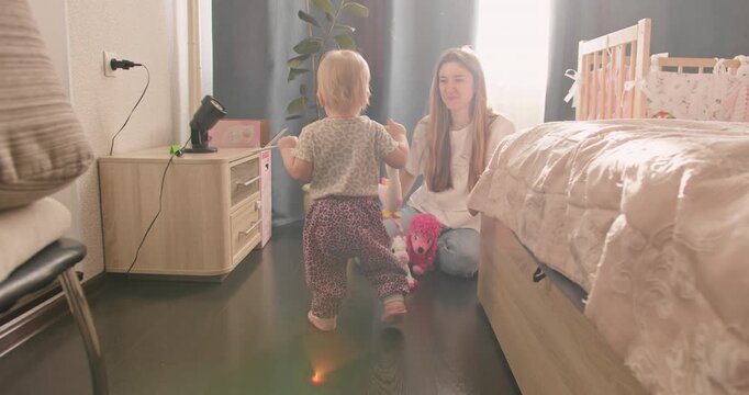 Parent supervising toddler learning to walk. Everyday childcare and child development at home