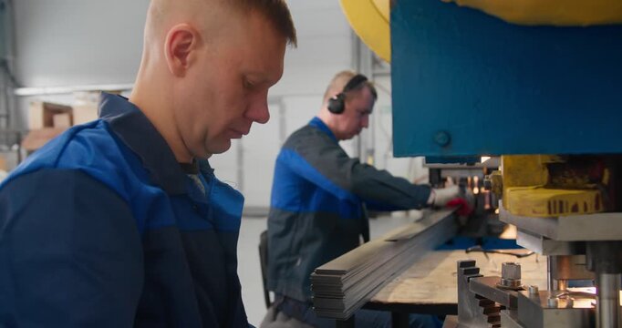 Industrial blue collar labor producing metal parts through hands-on operation of mechanical press equipment
