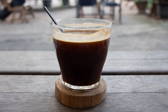 Americano coffee on wooden coaster with defocused background of rumah pohon (tree house caf&eacute;) in Jakarta, Indonesia - July 25th 2026
