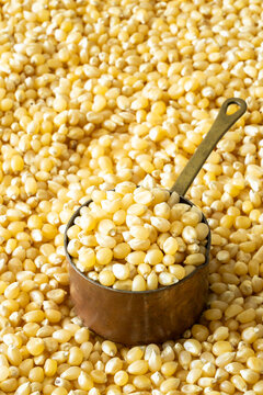 Closeup of un-popped kernels of popcorn with a copper measuring cup 