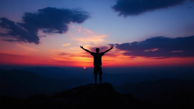 Silhouette of a man with arms raised in success on a mountain top enjoying the freedom and the beautiful sunrise, celebrating life and achievement with happiness