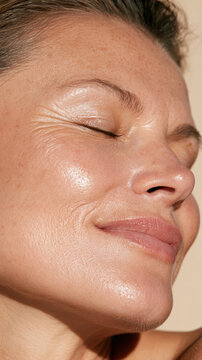 Woman with natural glowing skin and wrinkles closing eyes and smiling, embracing skin aging gracefully, a close up portrait showing authentic beauty and wellness