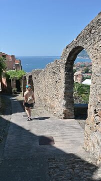 Cervo, liguria, italy. June 22, 2025. Young tourist woman strolling down a picturesque cobblestone alley in the historic village of cervo, enjoying a sunny day on the italian riviera