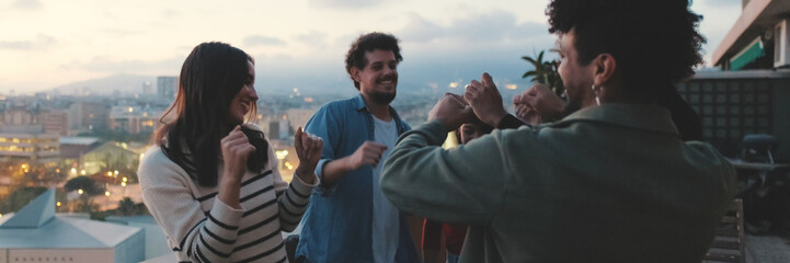 Fototapeta premium Guys and girls at party, dancing and having fun on the terrace, friendly party holiday at sunset. Panoramic