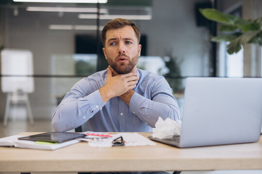 Businessman suffering from sore throat at work, feeling sick and unwell, experiencing flu or cold symptoms