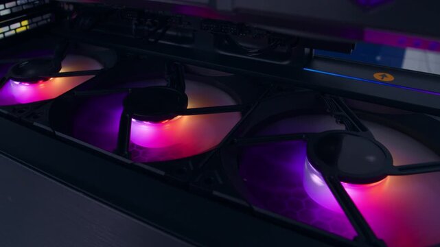 Extreme close-up of the colorful fans spinning on the computer's GPU illuminated by colorful LED lights
