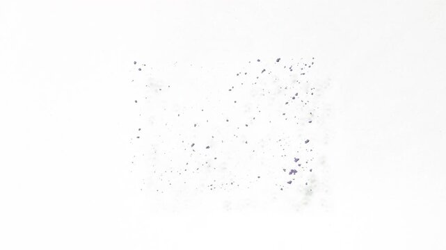 Top-down perspective slow-motion shot of violet powder sifting into rectangular form on white field swept away with a flow of air