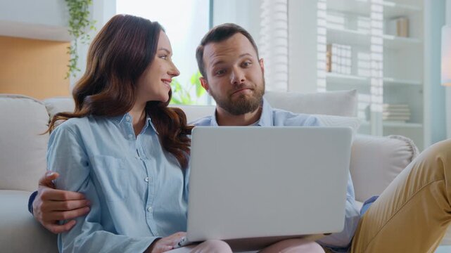 Happy family Caucasian looking in laptop hugging cuddling talking choosing ecommerce goods shopping with internet together man with woman hug talk buying choose purchases with computer at home