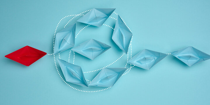 A red paper boat leads blue boats connected by dotted lines