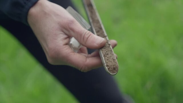 Scientist analyzing a ground sample with a soil probe for environmental research in a field