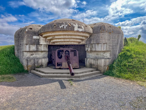 WWII German concrete bunker with original 150mm artillery gun at Longues-sur-Mer battery, Normandy, France. Part of the Atlantic Wall coastal defense near D-Day landing beaches.