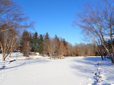 Snow covered Silver Park in Alliance, Ohio looking across Lake Kidwell at the island on a beautiful winter afternoon in January with a blue sky in January 2025