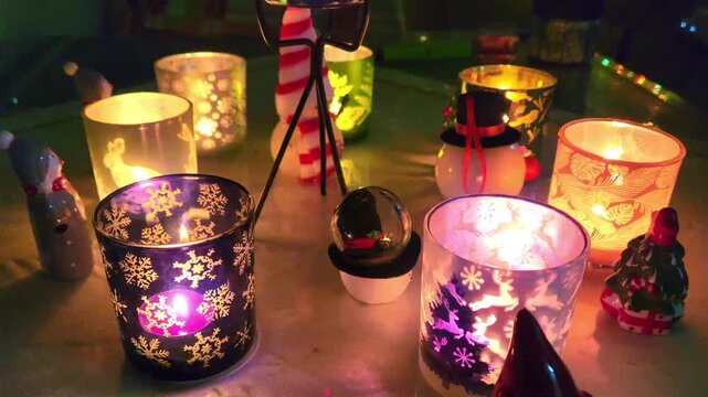 Table prepared for the new year: candles, Christmas lights, figurines, and Christmas themed glasses.