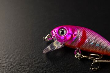 Pink fishing lure resting on dark surface The Concept of predator angling © VicVaz