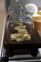 trozos de queso cremoso y suave en un tabla de madera tapados con una fuente de cristal de cúpula © planeta11